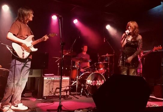 Me standing on the left side of the stage looking at the vocalist standing on the right side of the stage.