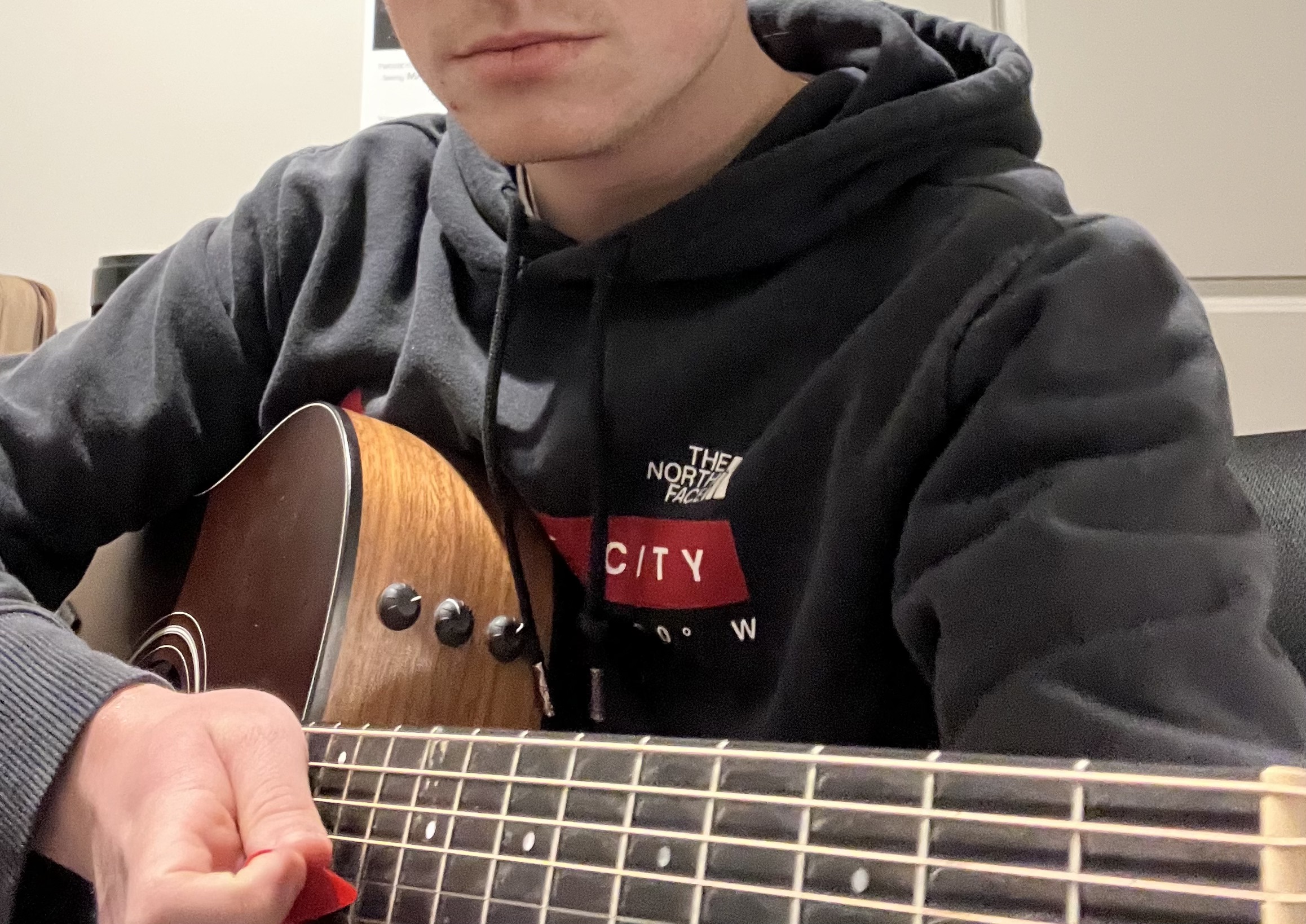 A black and white closeup of the bottom of my face and the top of my acoustic guitar.
