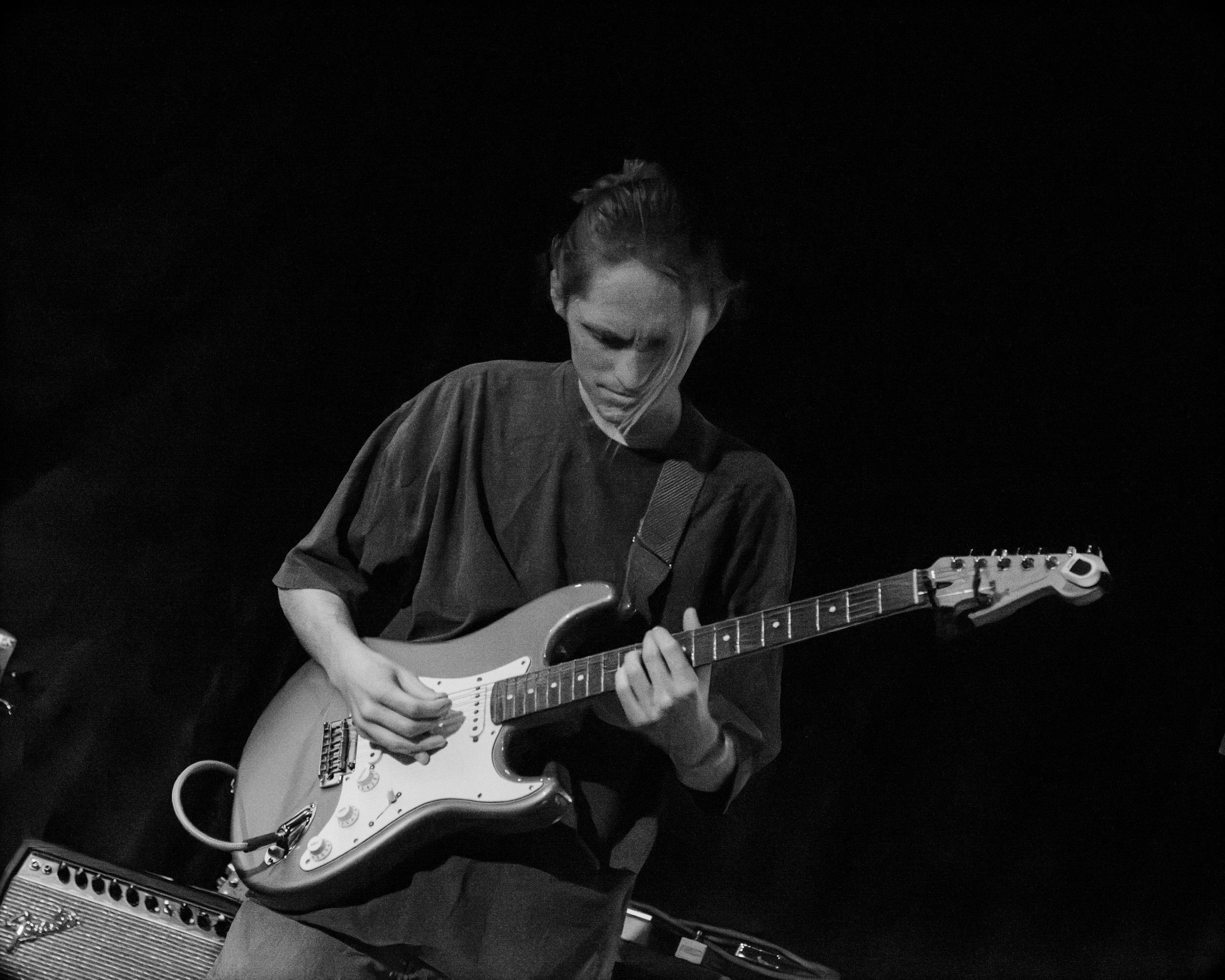 A black and white closeup of my face as I stand on stage playing guitar.